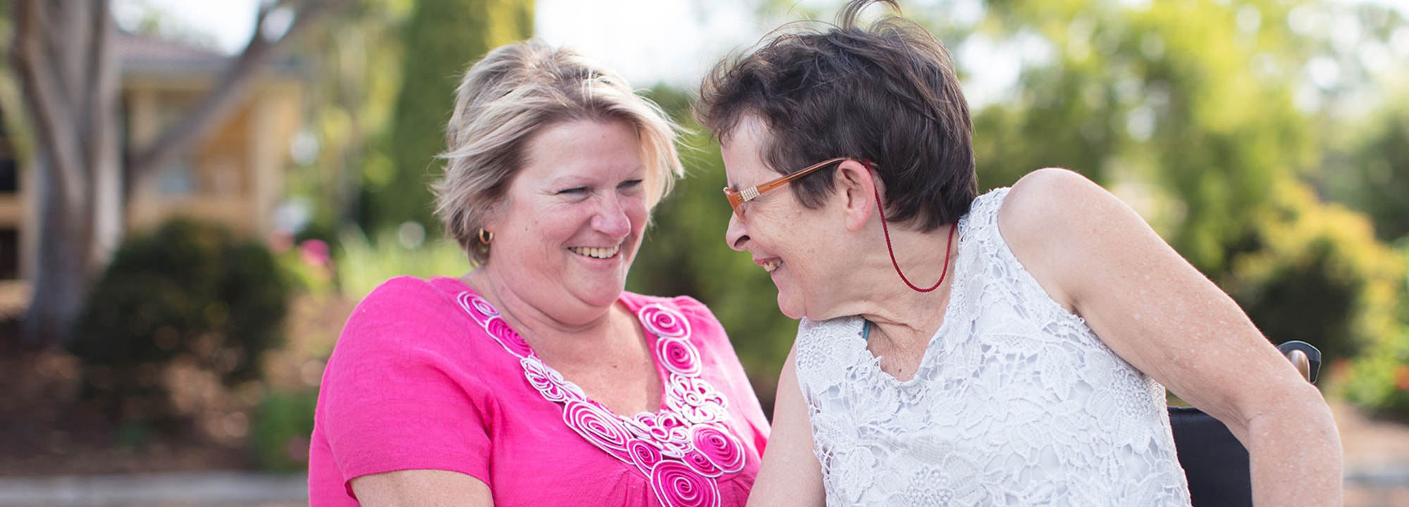 two elderly ladies sitting outdoors smiling