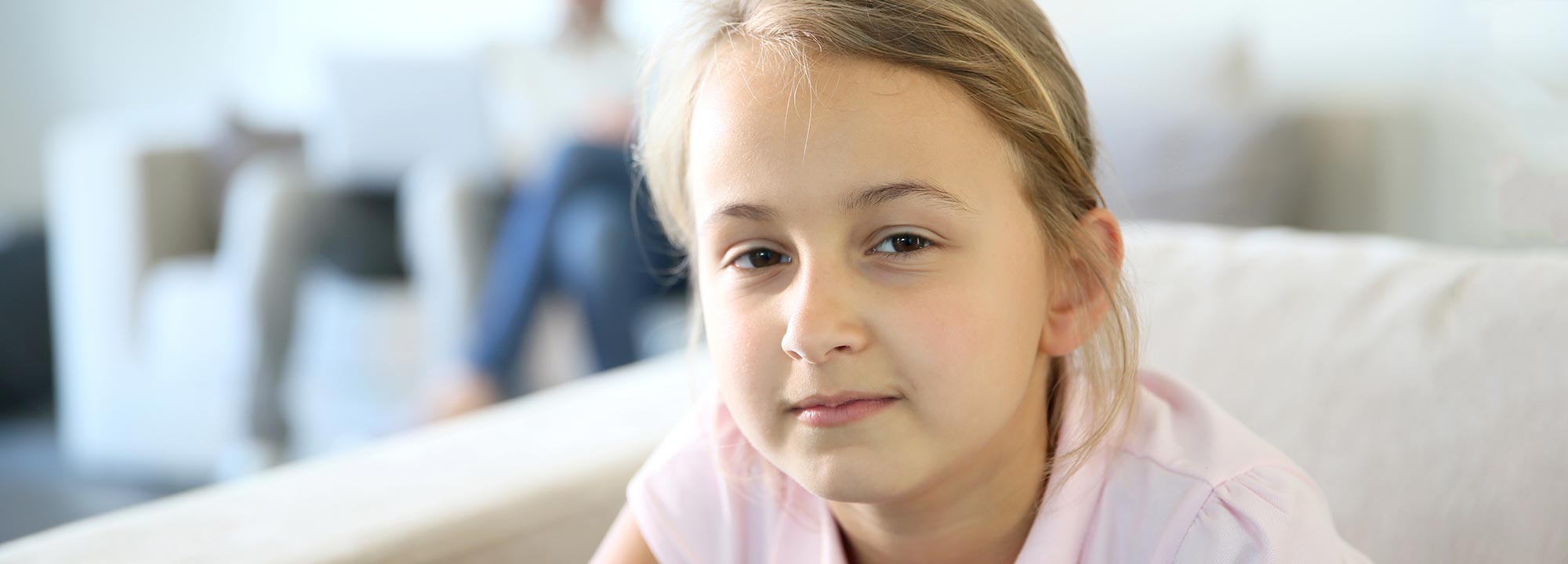 Girl looking at camera with parents in background
