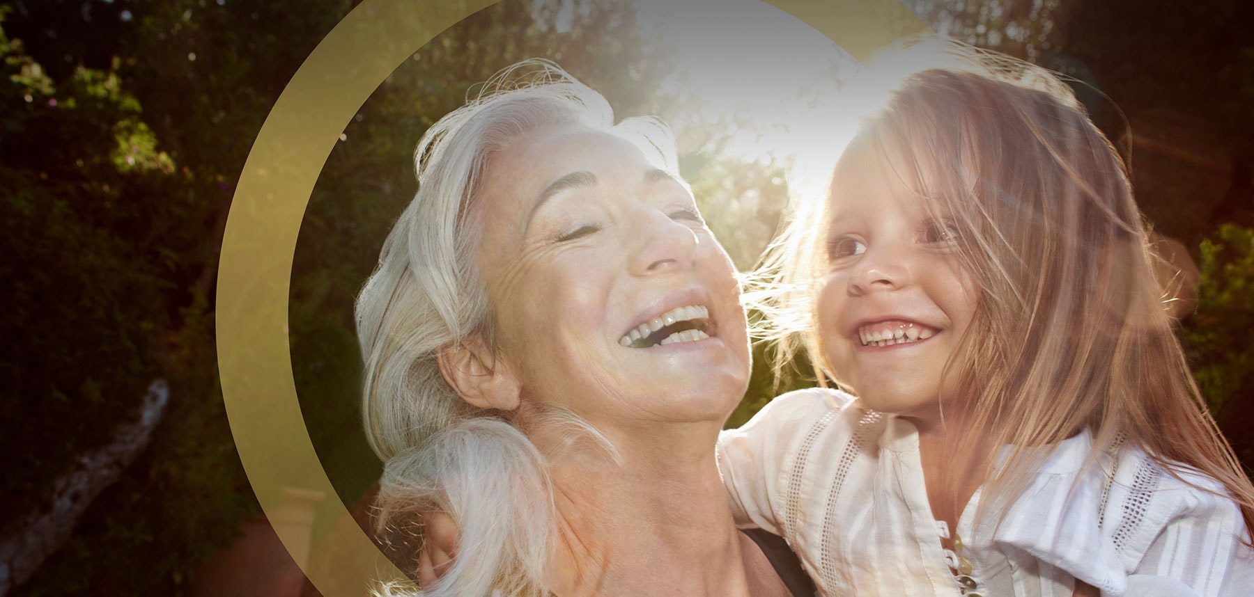 grandmother holding her granddaughter outdoors smiling