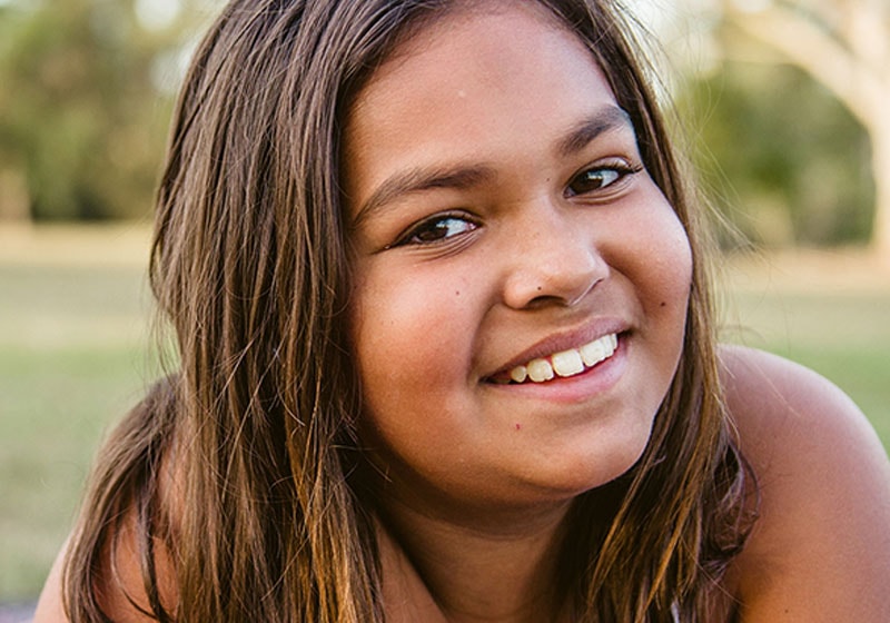 young indigenous girl laying down in park