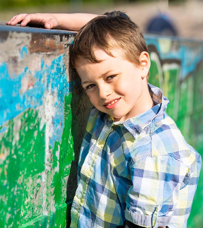 A young boy rests his head against a graffiti-covered wall.